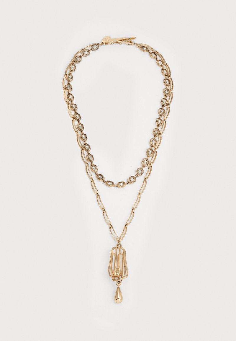 Collier en or superposé avec deux styles de chaînes différents et un pendentif avec un charme en forme de goutte au bas.