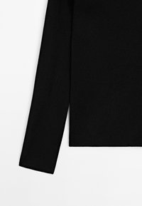 Maglietta nera a maniche lunghe con un design semplice. Realizzata in tessuto morbido, presenta una vestibilità dritta e uno stile minimalista.