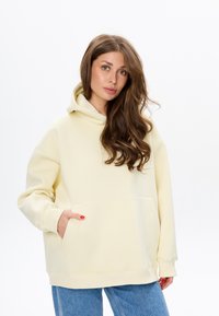 Helle gelbe Kapuzenpulli aus weichem Stoff, mit einer vorderen Kängurutasche, Kordelzugkapuze und gerippten Bündchen. Legere, übergroße Passform.