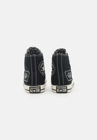 Zapatillas deportivas altas de lona negra con costuras blancas, forro de estampado de leopardo y detalles con el logotipo en el talón y los laterales. Acentos de diseño vintage.