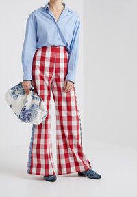 Sinine pika varrukaga särk, punase ja valge ruudulise mustriga laiad püksid sinise servaga ning mustriline käekott. Väljanägemine sisaldab erinevaid tekstuure.