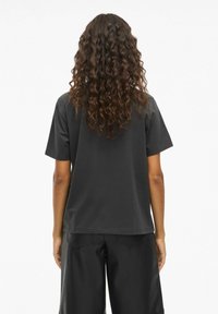 Sort kortærmet t-shirt lavet af bomuld, vist fra ryggen. Har en afslappet pasform og lige søm, glat tekstur.