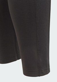 Bermudas deportivas negras hechas de material elástico, con costuras planas y un diseño ajustado. Textura suave con una estética limpia y minimalista.