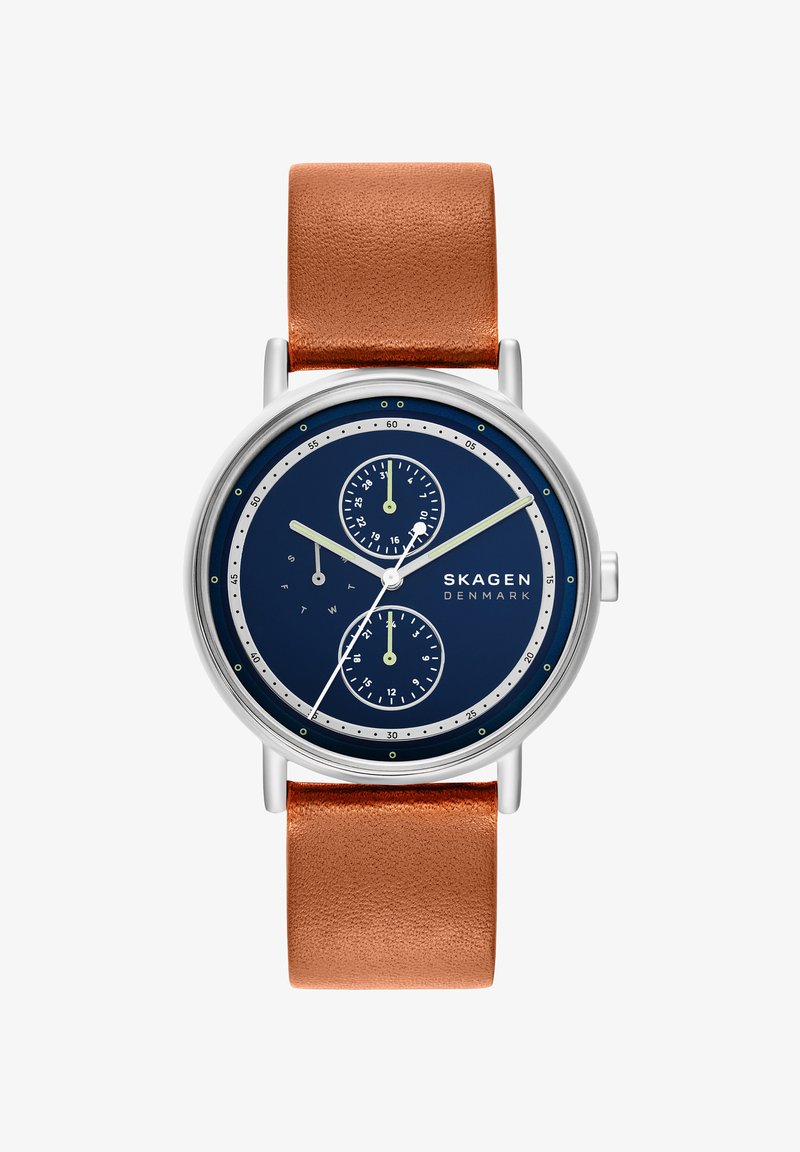 Orologio rotondo in argento con quadrante blu navy, cinturino in pelle color cuoio, due sottoquadranti per data e ora 24 ore e lancette bianche per ore, minuti e secondi.