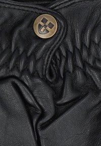 Czarna skórzana tkanina z przeszytym wzorem oraz okrągłym metalowym guzikiem z logo. Powierzchnia wydaje się miękka i lekko pomarszczona.