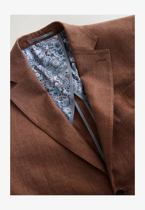 Blazer marrone in tessuto texture, con una fodera a motivo floreale blu e piping grigio lungo i bordi interni.