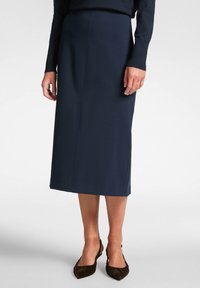 Marinblå midi kjol i ett stretchigt material med rak skärning och sidoseams. Kombinerad med bruna platta skor med en samlad textur.