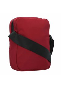Borsa a tracolla rossa in nylon con forma rettangolare, manico nero e chiusura con zip. Presenta una texture liscia e un design minimalista.
