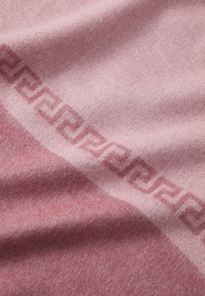 Couverture en laine rose présentant une texture douce, des nuances dégradées de rose et un subtil motif géométrique Greca le long d'un bord.