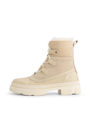 Beige suede laarzen met een voering van bont, een gequilt ontwerp bij de teen en vetersluiting. Dikke rubberen zool met een gestructureerd oppervlak en logo-detail aan de zijkant.