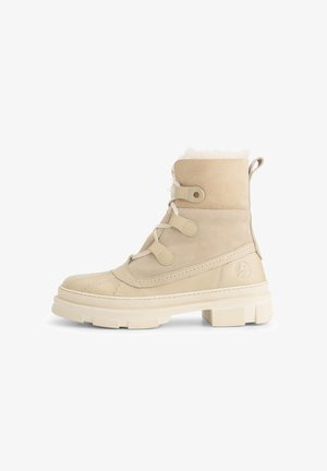 Beige suede laarzen met een voering van bont, een gequilt ontwerp bij de teen en vetersluiting. Dikke rubberen zool met een gestructureerd oppervlak en logo-detail aan de zijkant.