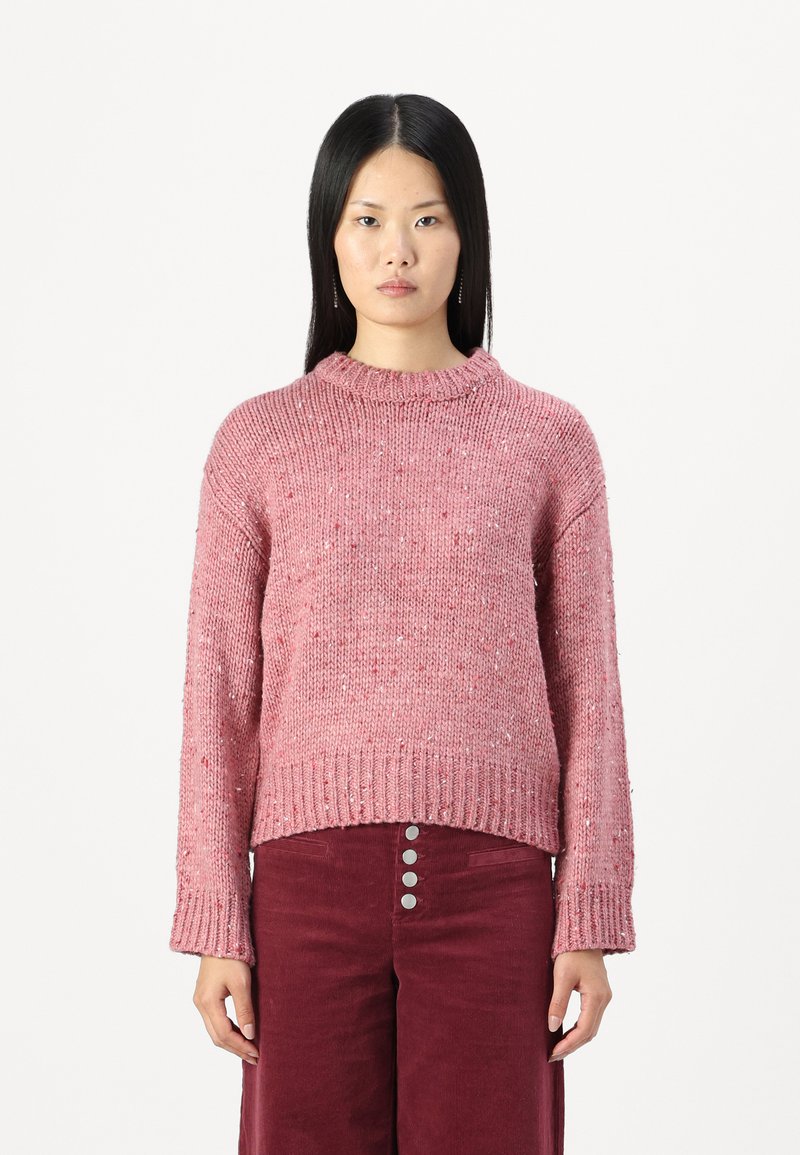 Maglione rosa lavorato a maglia con colletto e orlo a coste, caratterizzato da un motivo testurizzato e leggere macchie, abbinato a pantaloni in corduroy bordeaux.
