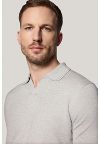 Szara, krótko rękawowa koszulka polo z dekoltem w kształcie litery V, charakteryzująca się miękką strukturą i minimalnymi detalami szycia.