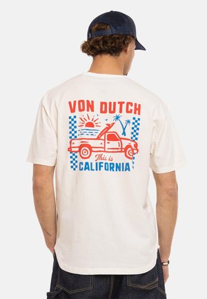 Homme portant un T-shirt blanc avec un graphisme rouge et bleu représentant un pickup, le soleil, des palmiers et le texte "Von Dutch This is California" au dos.