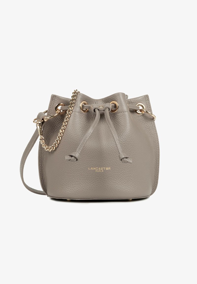 Petit sac seau en cuir taupe avec fermeture par cordon, détails en chaîne et anneaux dorés, et inscription "LANCASTER PARIS" en lettres dorées embossées.