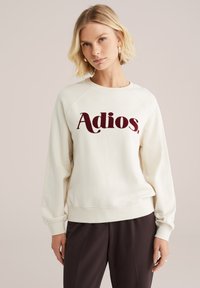 Kermansattainen huppari, jossa on maroon-värinen "Adios." -painatus. Huppari on valmistettu pehmeästä materiaalista, ja siinä on rento malli sekä ribbitaskut.