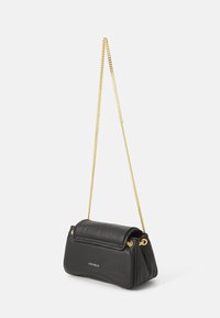 Sac à main en cuir noir avec une forme rectangulaire douce, doté d'une bandoulière en chaîne dorée et d'un logo de marque embossé à l'avant.