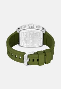 Orologio con cinturino in silicone verde e retro in acciaio inossidabile. Forma rettangolare, superficie texturizzata e logo "POLICE" inciso. Accenti metallici argentati.