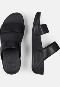 Zwarte slide-sandalen hebben twee brede banden met een gestructureerde afwerking, een platte zool en een open achterkant voor gemakkelijk aan- en uittrekken. Gemaakt van synthetisch materiaal.