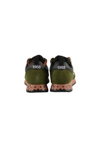 Sneakers in suede verde con tacco nero e dettagli arancioni. Caratteristiche notevoli includono una suola in gomma marrone a motivo e "1968" sul retro.