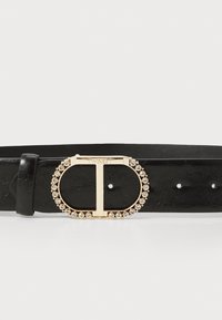 Black leather belt featuring a gold oval buckle surrounded by rhinestones, with a textured finish and multiple adjustment holes.