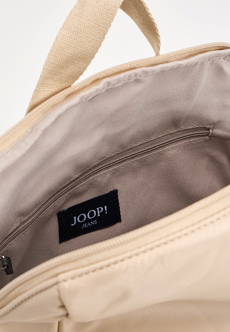 Innenansicht einer beigen Stofftasche mit glatter Textur, ausgestattet mit einer Reißverschlusstasche und einem schwarzen Etikett "JOOP! JEANS". Minimalistisches Design.