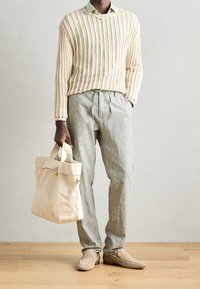 Pull en tricot crème, chemise à col vert clair, pantalon en lin gris, sac fourre-tout beige et chaussures slip-on beiges. Texture remarquable et coupe décontractée.