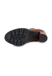 Brown leather heeled shoe sole with deep tread design, textured black rubber, featuring pointed ridges and a small branded emblem.