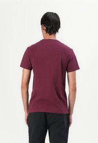 Bordeaux kortermet T-skjorte laget av bomull, med rund hals og en jevn tekstur. Enkel design uten synlige mønstre eller logoer.