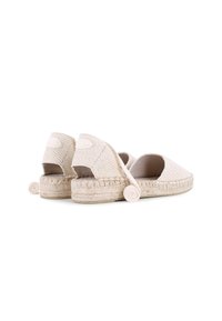 Espadrilles beiges con textura trenzada, diseño de parte trasera abierta y acentos decorativos en espiral en el tacón. Elaboradas con suelas de yute trenzado.
