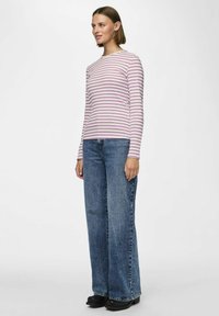 Rožinė ir balta juostuota ilgomis rankovėmis marškinėliai, derinami su plačiomis mėlynomis džinsinėmis kelnėmis. Turi apvalų kaklą ir laisvą siluetą.