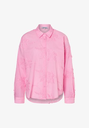 Blouse rose brodée avec des motifs floraux, une fermeture à boutons sur le devant, des manches longues et un ourlet incurvé, avec une texture douce.