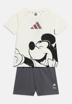 Biała koszulka z krótkimi rękawami z dużą uśmiechniętą grafiką Myszki Miki oraz bordowym logo Adidas, zestawiona z gładkimi ciemnoszarymi szortami z logo Adidas i Disney.