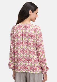 Langärmlige Bluse aus leichtem Stoff, mit einem bunten geometrischen Muster in Rosa, Gelb und Weiß. Mit elastischen Bündchen.