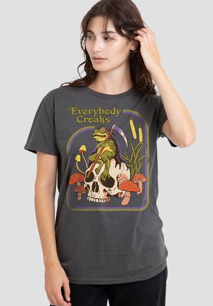 Woman wearing dark gray T-shirt with a frog holding a scythe sitting on a skull surrounded by mushrooms and cattails, text "Everybody Croaks."