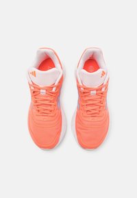 Baskets de sport en corail vif avec des accents blancs, tige en mesh et semelles texturées. Comprend des lacets et un détail de talon de marque en bleu clair.