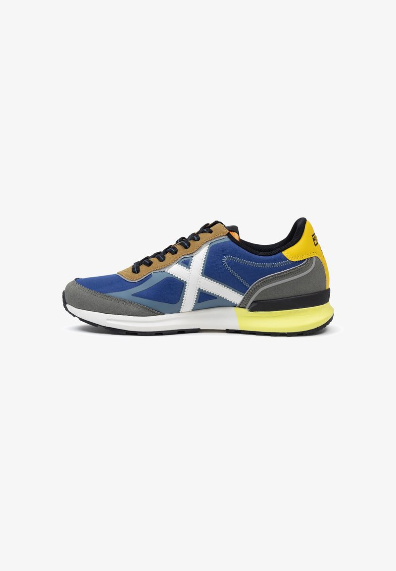 Zapatilla multicolor con nylon azul, ante marrón, detalles grises, logotipo blanco y suela amarilla. Diseñada con cordones y un cuello acolchado.