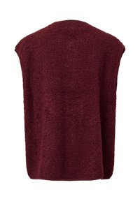 Vinröd fleeceliknande poncho med en mjuk, strukturerad yta, vida ärmhål och en rund halsringning. Bakifrån ses en avslappnad, ostrukturerad passform.