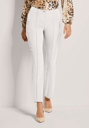 Weiße, maßgeschneiderte Hosen mit dezenten vertikalen Nähten und einer glatten Textur. Kombiniert mit Nude-Absätzen und einer gemusterten Bluse.