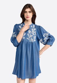 Abito in denim di un blu intenso con motivo floreale ricamato sul corpino. Presenta maniche a sbuffo e chiusura a bottoni sul davanti.