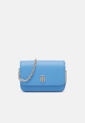 Niebieska skórzana torebka crossbody z złotym łańcuszkiem i złoconymi inicjałami na przedniej klapie, ustawiona na białym tle.