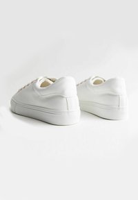 Vita sneakers med en texturerad läderövre, rund tå och platt gummisul. Utrustade med vävda snören och en minimalistisk design.