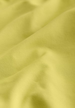 Tela amarillo claro con una textura suave, mostrando suaves ondas y pliegues, resaltando su plasticidad y suavidad.