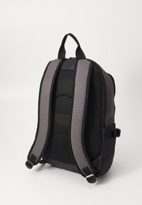 Sac à dos noir et gris avec des bretelles rembourrées en mesh, une poignée supérieure et un corps à texture lisse doté d'une fermeture éclair.