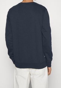 Tummansininen collegetakki pitkillä hihoilla, ribbineulotut hihansuut ja helma, puuvillasekoite, sivulla helman lähellä silmukka.