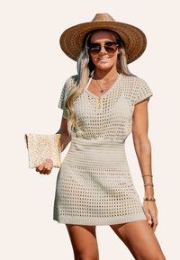 Abito lavorato a maglia beige chiaro con maniche corte, scollatura a V e bottoni dorati decorativi. Abbinato a un cappello di paglia e una borsa a tracolla intrecciata.