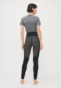Sportos leggings magas fekete derékkal, hátul és a felső lábakon fekete-fehér texturált mintázattal.