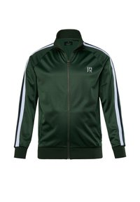 Chaqueta verde con cremallera hecha de poliéster brillante. Presenta franjas laterales blancas y puños y dobladillo acanalados. Logo en la parte izquierda del pecho.