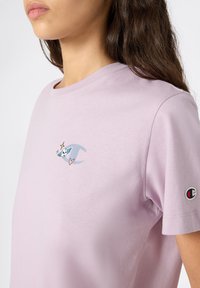 Lilac cotton T-shirt featuring a small graphic with a skull, heart, and wings; short sleeves; and logo detail on the left sleeve.