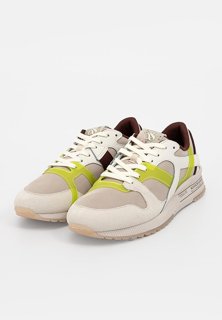 Baskets beige clair avec des accents verts, en maille texturée et en daim, avec un système de laçage et des semelles en caoutchouc ; comprend un détail de marque subtil.